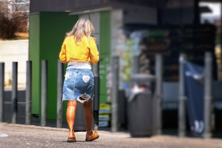 Back view of a woman walking in the street. Blurred background.の写真素材