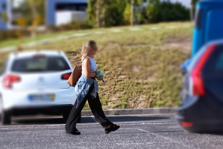 Young woman crossing the road on a sunny day. Blurred backgroundの写真素材
