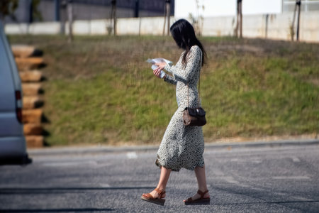 A young woman is walking on the street and holding a cup of coffeeの写真素材