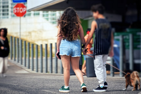 Rear view of a teenage boy and girl walking on the streetの写真素材