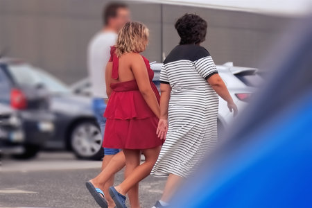 Rear view of young couple walking on the street with cars in the background