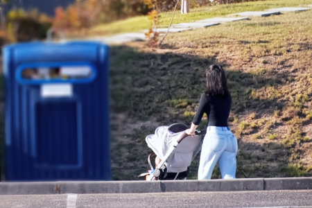 Young mother walking with baby stroller on the street in autumn.の写真素材