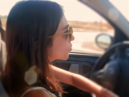Young woman driving a car on a sunny day in summer.