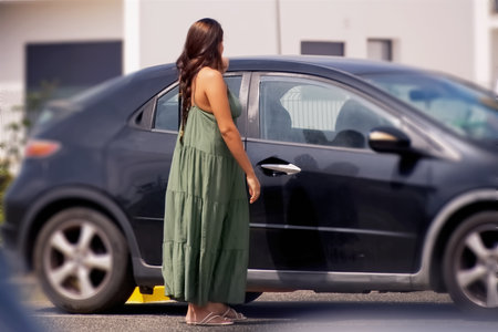 Young woman standing near the car on the street. Rear view.の写真素材