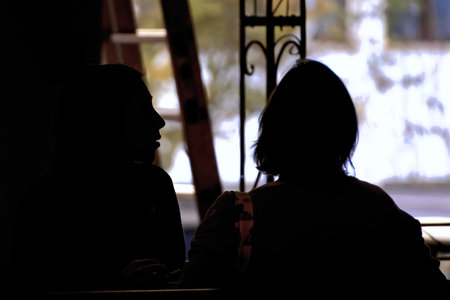 Silhouette of two women sitting in a cafe at sunset.の写真素材