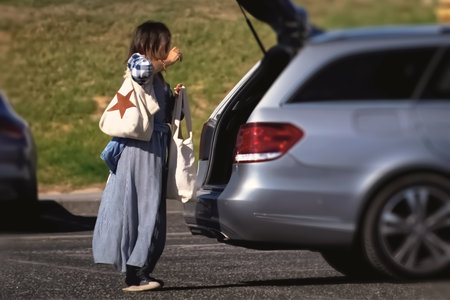Woman with backpack standing on the road and looking at her car