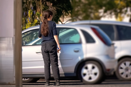 Young woman standing in front of a car and waiting for her carの写真素材