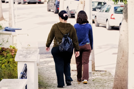 Rear view of a woman walking on the street with her friendの写真素材