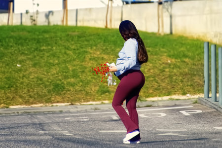 Pregnant woman with a bouquet of flowers in her hands on the streetの写真素材