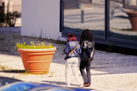 Two young women walking on the street and looking at the building.
