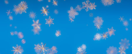 A mesmerizing image of snowflakes falling against a bright blue sky, capturing the essence of a winter wonderland.の写真素材