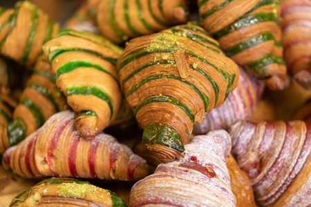 Assorted colorful croissants with pistachio and red glaze. Perfect for breakfast or dessert.