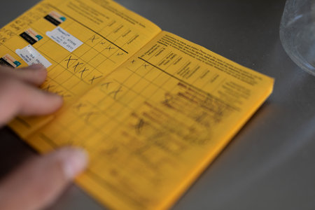 Hand Filling Out Yellow Vaccination Record Book
