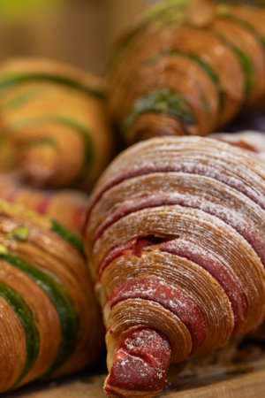 Close-up of freshly baked croissants with red velvet and pistachio flavors. Sweet pastries.