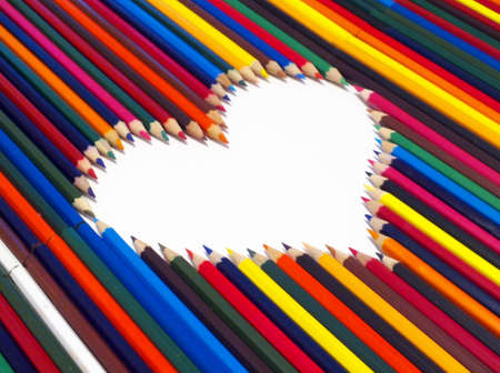 colored pencils, laid out in the shape of a heart on a white backgroundの写真素材