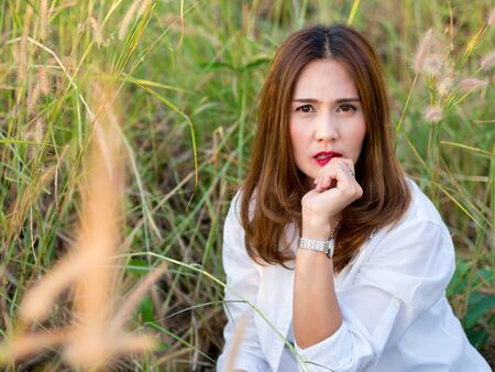 Asian beautiful Woman in the Meadow, wearing white shirt, On a sunny days. sexy woman concept.の写真素材