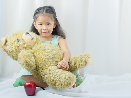 asian child smiling And holding teddy bear, Apples. Food needed for children, concept.の写真素材