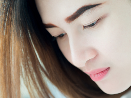Portrait of Asian woman in white vest, expressing the idea of broken heart and sadness. hopeless and await, concept.の写真素材