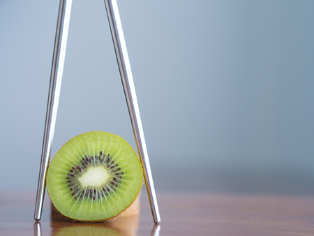kiwi fruit in chopsticks on a wooden table. Healthy fruit concept.の写真素材