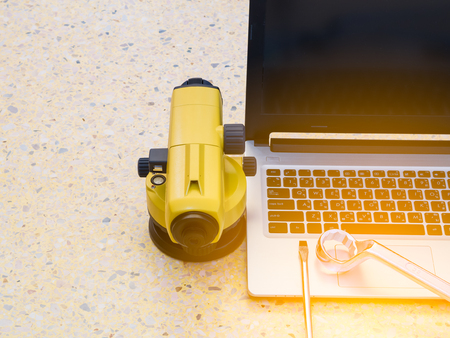 surveyor's telescope,  Notebook Computers and wrench on floor. Construction industry concept.