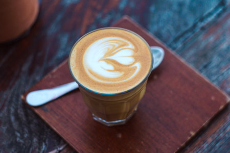 Hot latte art coffee on wooden table in coffee shop, stock photoの写真素材
