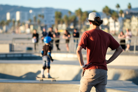 Venice Beach Skatepark, man looking at a kid learning how to skateのeditorial素材