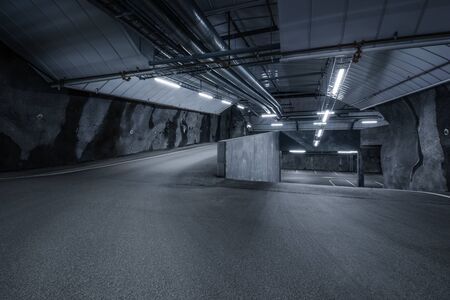 Sci-fi looking dark and moody underground parking lot with fluorescent lights on.