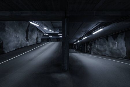 Sci-fi looking dark and moody underground parking lot with fluorescent lights on.