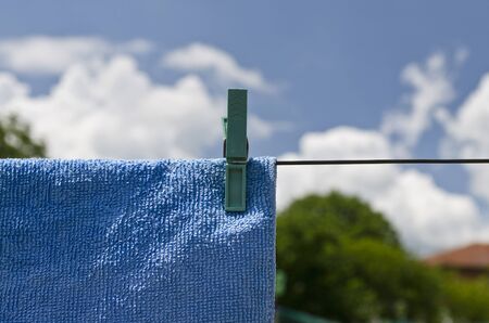 Clothes peg on a blue towel and washing line against a blue sky