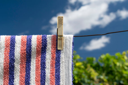 Clothes peg on a towel and washing line against a blue skyの写真素材