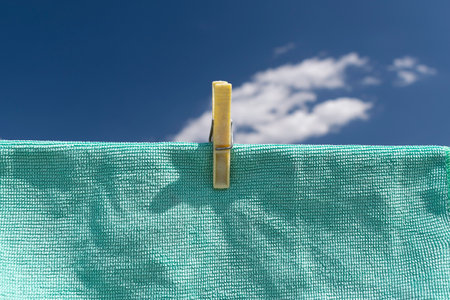 Clothes peg on a towel and washing line against a blue skyの写真素材
