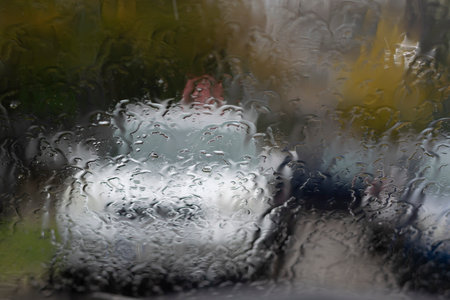 Raindrops on the glass window with outline of a car