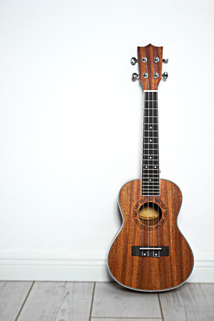 Wooden ukulele leaning against the wall