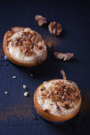 Baked pears with cottage cheese, honey and walnuts on dark backgroundの写真素材