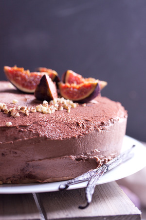 Homemade chocolate pie with fresh figs, nuts and cacao powder on a wooden boardの写真素材