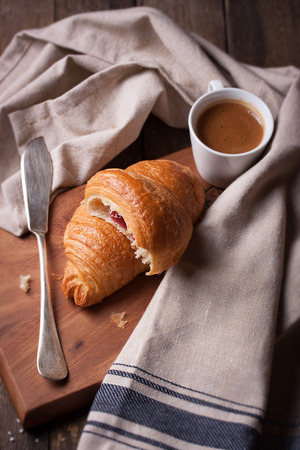 Croissant with jam and coffee on a wooden background. Top viewの写真素材