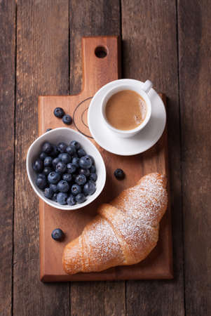 Croissant with coffee and blackberries on a wooden board. top viewの写真素材