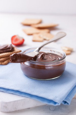 Chocolate sweet melting nougat cream in a glass jar with knife, closeup, selective focusの写真素材