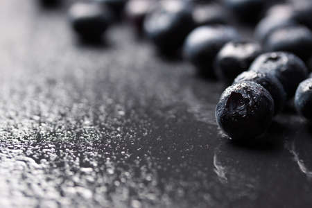 Closeup of fresh ripe blueberries on a black stone background with copy space, selective focusの写真素材