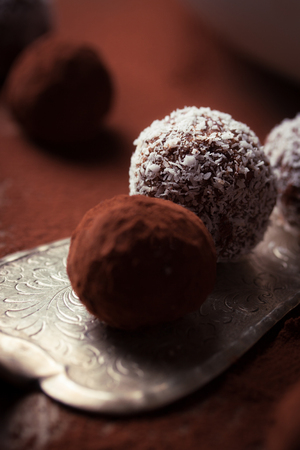 Chocolate sweets with cocoa and coconut chips on a white plate, selective focusの写真素材