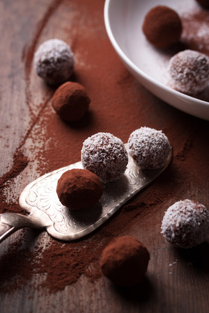 Chocolate sweets with cocoa and coconut chips on a white plate, selective focusの写真素材