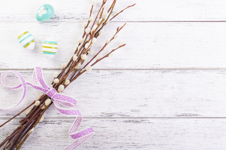 Colorful Easter eggs with willow branches and lila ribbon and copy space on a wooden background, top viewの写真素材