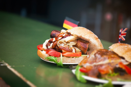 Street food german burger with sausage, vegetables, ketchup and mayonnaise. Street food or unhealthy food concept. の写真素材