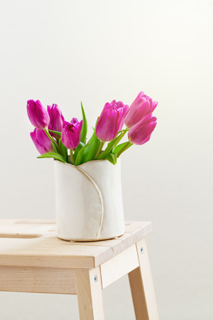 Beautiful Fresh Spring lila Tulips in Vase on Wooden Stool. Spring, easter or Mother's Day Concept. の写真素材