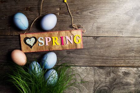 Easter Eggs on Fresh Green Grass on Wooden Background with Sunny Light Beams. Horizontal with Copy Space. Easter or Spring Concept. の写真素材