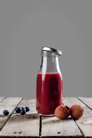 Tasty colorful fresh homemade red smoothie in glass jar on wooden table. Healthy, detox concept.の写真素材