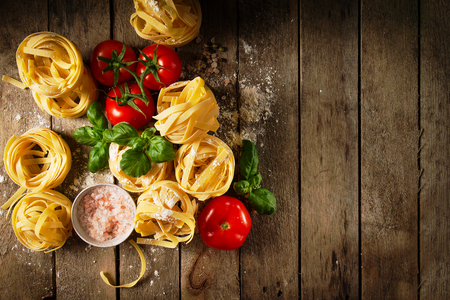 Tasty Fresh Colorful Ingredients for Cooking Pasta Tagliatelle with Fresh Basil and Tomatoes. Top View. Wooden Table Background.の写真素材