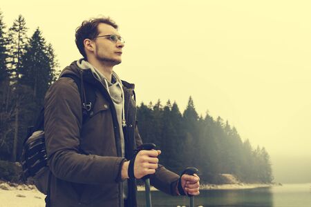 Young hiking man sportsman or traveler with backpack staying and looking on horizon. Toning.の写真素材