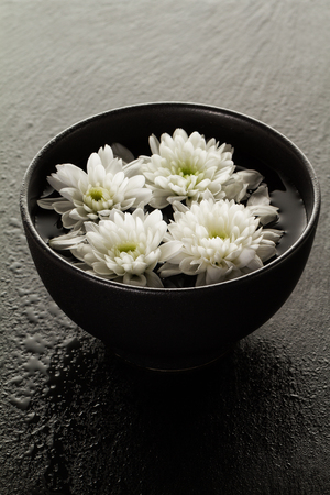 Spa Relax Concept. Beautiful White Spa Flowers in Bowl in Water. Dark Background. の写真素材