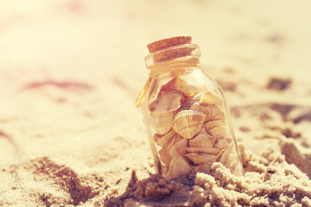 Summer or vacation concept. Seashells in bottles on sand. Toning.の写真素材